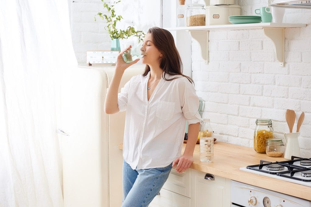 Woman drinking clean tap water from drinking water system