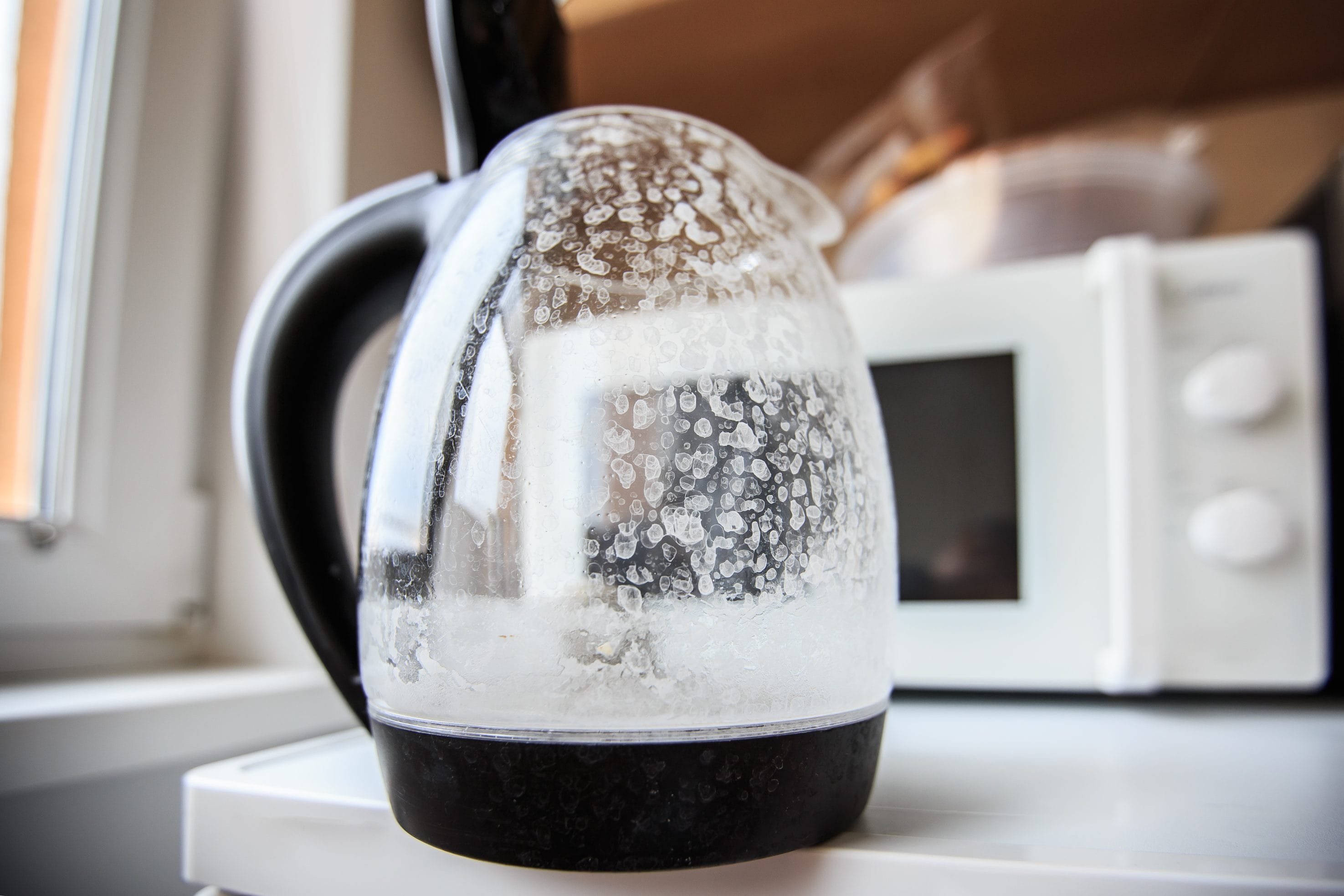 A glass electric tea kettle with lots of limescale from hard water.